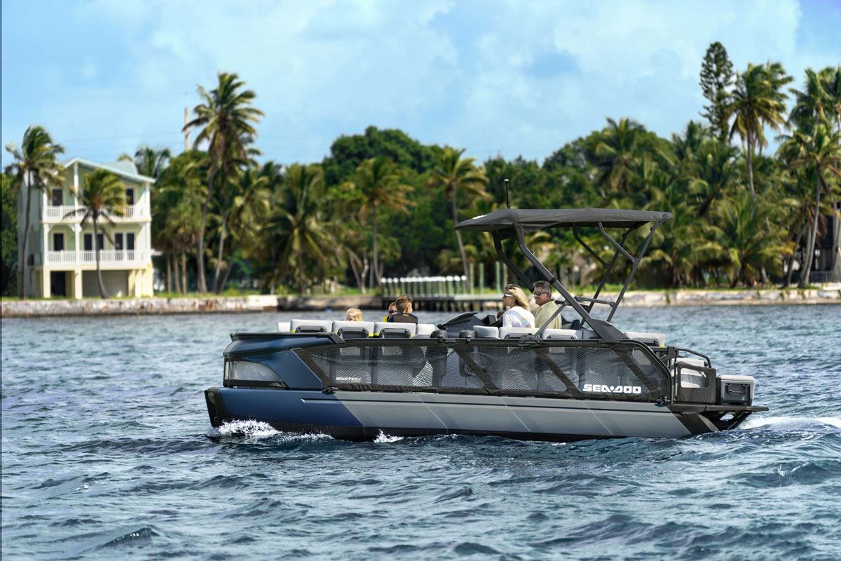 A Sea-Doo Switch jet boat carrying passengers on a Florida waterway lined with palm trees